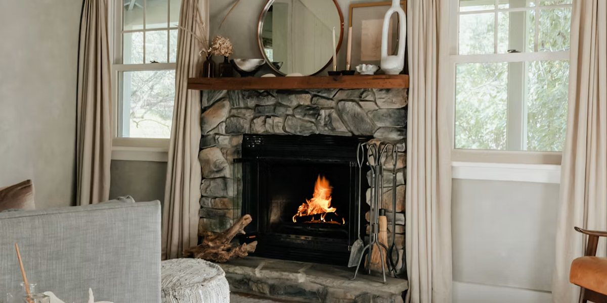 Stone fireplace with a lit fire between two curtained windows