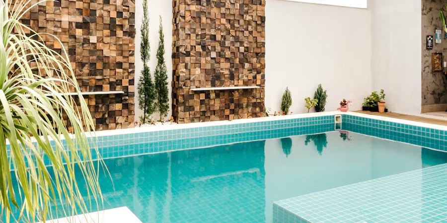 Turquoise tiled pool in front of stone-clad feature walls and slim cypress trees